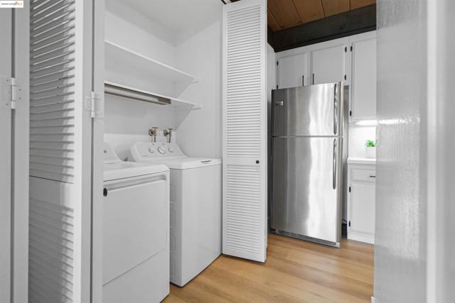 Laundry area featuring light wood-type flooring, washing machine and dryer, and wood ceiling