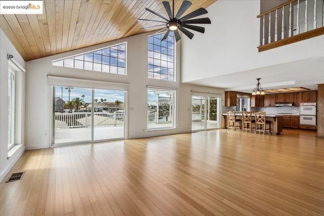 Unfurnished living room featuring a ceiling fan, light wood-style floors, a chandelier, wooden ceiling, and high vaulted ceiling