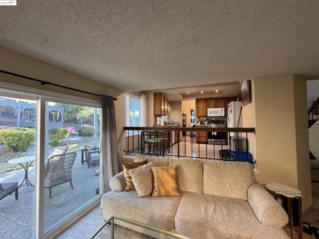 Living area featuring stairway, a textured ceiling, and light wood-style floors