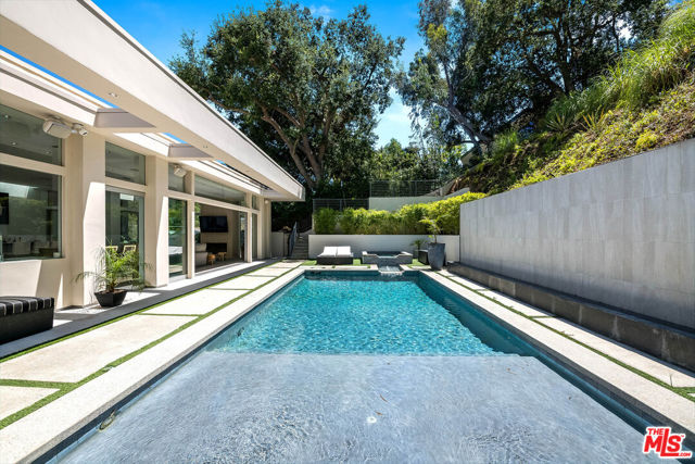 Stunning Contemporary on lower Bowmont Drive, just minutes from the heart of Beverly Hills. This fabulous home is an entertainer's paradise, boasting high ceilings, new porcelain & oak hardwood floors, & floor to ceiling windows & doors throughout welcoming light & opening to the wonderful exterior space. Incredible open chef's kitchen with large island, top-of-the line appliances, & adjoining family room. Great open living room & dining space with lit bar, glass-enclosed wine display, & walls of sliding glass that open to the spectacular backyard featuring pool, spa, built-in BBQ, firepit, & multiple levels of decks including a brand new basketball court. Wonderful master suite with private patio, fireplace, walk-in closet, & spa-like bath. 2 additional bedroom suites & 4th bedroom suite with built-in bookcases & private patio. 60 speakers, 10 cameras & retractable shades in all bedrooms. Completely private & secure. 24 hour local security patrol. 2-car garage.