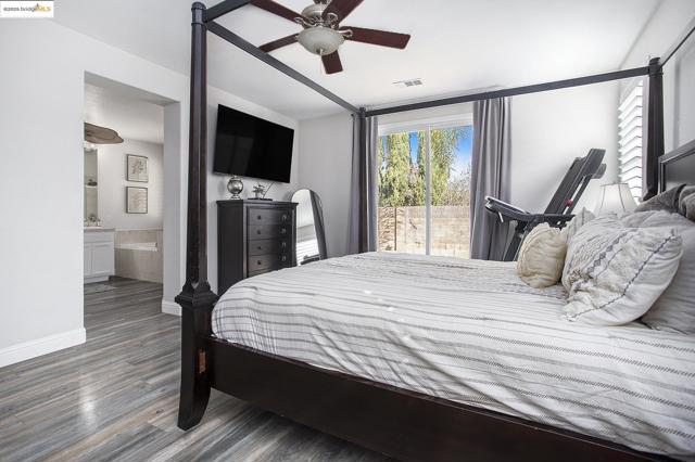 The primary bedroom with a laminate wood-style floor connects seamlessly with the primary bathroom
