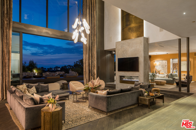 9152 Janice Place Beverly Hills, California Private gated home to one of the worlds most stylish celebrity couples. The grandeur begins in the parlor, with its 33-foot ceilings and sculptural staircase, and continues in the extraordinary living room, where floor-to-ceiling windows offer sweeping canyon views. Bespoke patterned ceilings from Thailand, cerused oak floors and clay and steel-rolled walls exude sensuality. The chefs kitchen befits a culinary influencer and cookbook author, and opens onto a large family room. The master bedroom features a brass and concrete fireplace, a balcony, a lush Glam Room, and exquisite, newly designed closets evocative of a Chanel showroom. A marble Teuco tub, onyx sinks and a double shower are the stars of the master bath. The design language continues in the backyard, with its heated saltwater pool and jacuzzi, wood-burning oven, chefs grill, and grapevine-wrapped pergola. Solar power and 70kW generator complete the estate. Only moments to The Beverly Hills Hotel and Rodeo Drive.