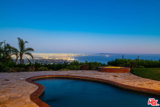 1360 Lachman Lane Pacific Palisades, California This fabulous home located on coveted Upper Lachman Lane in the extremely desirable Marquez Knolls neighborhood is perched on an almost 18,000 sq.ft. lot w/breathtaking panoramic views spreading from Catalina, Palos Verdes, & the Queens Necklace to Downtown L.A. Enter into this one-story home to the spacious living room w/vaulted, beamed & skylit ceilings, fireplace, & walls of French doors that open to the tranquil backyard & overlook the stunning views beyond. The wonderfully remodeled kitchen is complete w/granite countertops, professional appliances & adjoining dining area. Bedrooms consist of 2 guest or family bedrooms, office which could serve as a 4th bedroom, & primary suite featuring custom closet & lovely bathroom. There is also a laundry rm, powder rm & 2-car garage. The backyard completes a truly magical setting & offers great space for both relaxing & entertaining, featuring lawn, pool, spa & spacious patio w/built-in firepit, all framed by the magnificent views beyond.