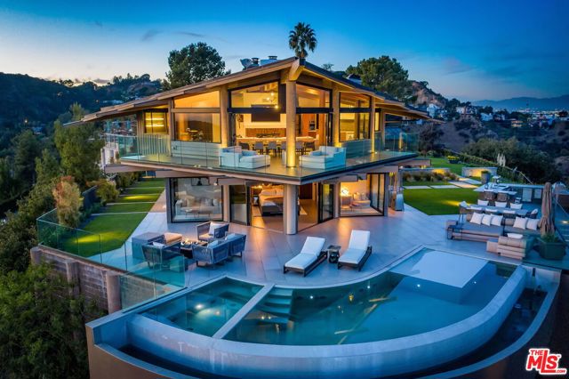 7000 Macapa Drive Los Angeles, California Simply unrivaled. This is the sexiest, most timeless, and architecturally impressive estate in the Hollywood Hills. Designed by Harry Gesner, and set on its own promontory behind private gates, this tour-de-force overlooks some of the most iconic views in all of Los Angeles and boasts extraordinary craftsmanship with a stylistic confluence of modernity and sophistication that redefines all expectations. The top-level offers a chef's kitchen, spacious living and dining area with a custom-built bar, and separate office. Down the elevator, the owner's suite and bathroom have unparalleled views of the Hollywood Sign and the city skyline behind the infinity pool. The recording studio, detached from the main house, has been fitted with the best equipment the industry has to offer. 2-car garage and plenty of space for additional parking on the courtyard. This reimagined house celebrates the site and our 21st-century lifestyle and will be an architectural beacon for generations to come.