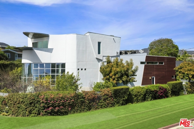 16988 W Marquez Avenue Pacific Palisades, California Positioned on a corner lot with its "bow" facing the Pacific, this spectacular architectural compound was designed with both comfort and style in mind. The dramatic living room with its curved wall of glass and steel is flooded with sunlight. A central courtyard allows the ground level rooms to flow outdoors, creating a space to connect and entertain, while retaining complete privacy. The gourmet eat-in kitchen exudes a contemporary European flair. At thelower level, a generous space functions as a media room/theater or game room, with state-of-the-art audio/visual. Take the elevator up to the top floor, where an expansive primary bedroom suite reveals a view of the ocean. With over 7,000 sf of living space, a 3 car garage and even a sauna, this estate is a rare contemporary just moments from the surf and the boutiques+ restaurants Palisades Village!