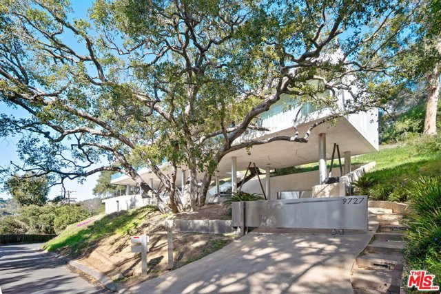 9727 Oak Pass Road Beverly Hills, California Published in the Robb Report, French Elle, and most recently in California Homes Magazine. This internationally praised architectural masterpiece is cleverly designed and sculpted into the hillside, surrounded by majestic oak trees with panoramic canyon views from nearly every angle. Nestled on one of the most sought after, private gated streets in Beverly Hills. The impressive residence is constructed to emphasize its natural environment, elegantly perched above ground at birds eye view. The natural flow of light, serenity and privacy offers a seamless fusion of indoor and outdoor living. The separate spacious studio with kitchenette, bath, and lounge could function as a screening room or guest house, currently used as a home office. Design by Heusch Architecture for stylish luxury living and entertaining.