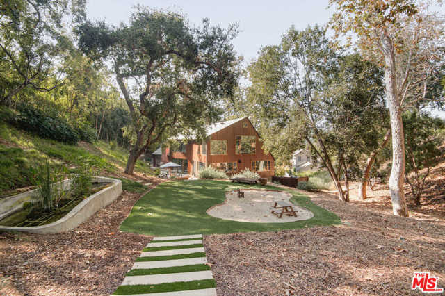 5720 Valley Oak Drive Los Angeles, California Nestled among mature Sycamore and Oak trees and located in the private and gated enclave of Valley Oak Drive, this hidden compound is inspired by the Great Lakes of Minnesota and the Colorado Rockies. Gated and set above a large motor-court, a stone walk-way leads to the main residence with a front door that opens to a seamless space of living, dining, kitchen and family areas. Generous walls of glass overlook the patios and terraced yard creating an incomparable feeling thats both intimate and expansive. As part of the main residence, a sky lit staircase leads to the second floor and gives one the serenity of being perched in the trees. It features a beautiful master suite with bath plus a second bedroom with full bath. From the main house a private walk guides you to a full guest house.