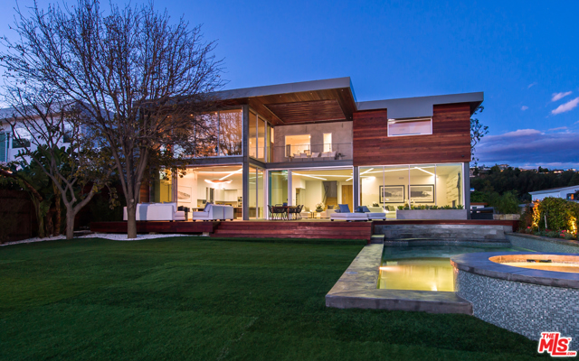 2511 Carman Crest Drive Los Angeles, California Set in the highly sought-after Outpost Estates, this modern architectural home offers the grandeur of expansive indoor-outdoor living w/breathtaking city views. Spanning nearly 5,000 square feet incapsulated by soaring ceilings & white oak floors, the masterfully designed open floor plan feat. 5 bdrms, 6 bthrms, wine cellar & office. From the living room, dining room & kitchen, walls of glass vanish opening up to the backyard positioned atop the Los Angeles skyline. The custom kitchen is suited with top-of-the-line appliances, a waterfall island & breakfast bar, all open to the other main entertainment spaces. Upstairs, the Master Suite is complete w/ a private balcony, walk in closet & a jaw dropping stone filled bathroom w/ a free-standing tub looking over the entire city. Perfect for both entertaining & relaxation, the backyard hosts a pool, elevated spa, & lush grass area. Fully equipped with the latest technology, the smart home allows for the most convenient living experience.