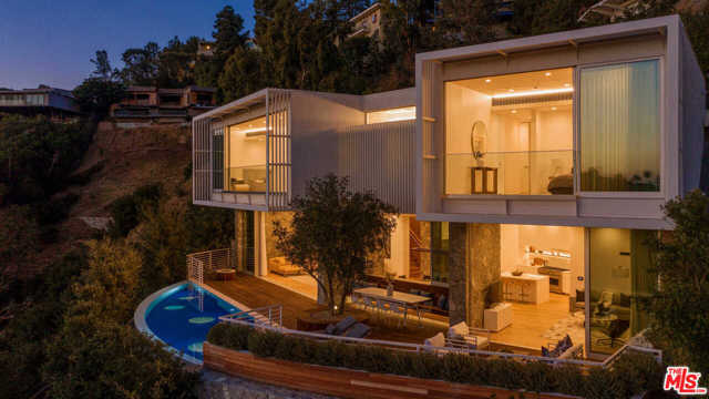 9469 Beverlycrest Beverly Hills, California Situated on a private promontory, this contemporary new architectural is nestled into the hillside capturing sweeping canyon, city & ocean views. Envisioned by architect Ivan Ivanov, the approx. 9,312-sq-ft home boasts hand-laid stone walls, 12 ceilings, oak floors from reclaimed 19th-century barn & modern chefs kitchen with Thermador appliances. Floor-to-ceiling glass walls connect indoor-outdoor living, opening to the infinity-edged pool with windows to the gym below. Expansive terraces boast a built-in BBQ and olive tree, among the 50 new trees planted onsite. 5 bedroom suites include 2 upper-level masters, both with a spacious soaking tub. The lower entertainers level features a stunning bar, 3,000-bottle wine cellar, gym & theater. Features include a Zen-inspired backyard with redwood hot tub & yoga deck, Carrera marble baths, elevator, KNX smart system & 2-car garage. This spectacular, private contemporary retreat is located moments from downtown Beverly Hills.