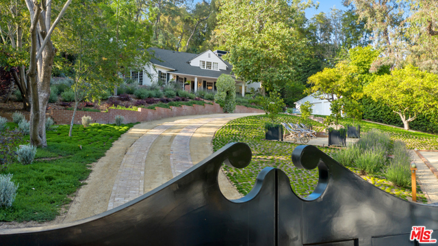 9305 HAZEN Drive Beverly Hills, California Rare, classic, Beverly Hills retreat. Once the home of Paul Newman and Joanne Woodward, the estate is 1.2 acres of privacy and serenity just 10 minutes from downtown Beverly Hills. Having undergone a recent preservation and renovation, the gated Colonial Revival on coveted Hazen Drive is surrounded by wooded paths, citrus trees, bocce court and pool. Entry gates reveal a sweeping brick driveway, European garden and bocce court. A rooftop cabana shades a modern, fully-equipped gym with gorgeous views of the pool and hiking trail. 4 ensuite bedrooms bring an elegant yet comfortable feel to this classic estate. The expanded kitchen is connected to a charming walk-in pantry with devoted wine storage. A den with oak herringbone floors. The classic design continues with the living room's handsome, black marble fireplace, and vintage French Club chairs. The outdoor loggia features a stone fireplace opposite a custom, swing sofa ideal for afternoon naps and evening wine . A rare, turn key gem.