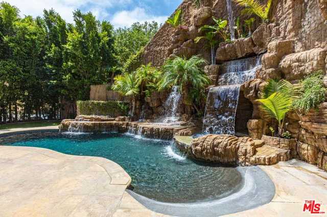 9821 Beeson Drive Beverly Hills, California Gated Beverly Hills estate on a private cul de sac. This gracious and elegant, five-bedroom, seven-bathroom estate boasts a grand entry with a curved staircase leading to three ensuite bedrooms and an impressive master suite with a romantic balcony and a sunny bathroom with spa tub. The entry showcases an incredible volume, scale, high ceiling, a formal living, and dining, gourmet chef's kitchen, and huge pantry, breakfast room, spacious family room, and a fireplace. French doors leading to resort-like pool and spa. On the lower level, there is a fifth ensuite bedroom and media room perfect entertaining. The hillside is a paradise of privacy with mountain and city views, terraced patios, fountains, and a courtyard for entertaining, two-car garage, and ample parking. The main level with Mahagony wood floors consists of formal living and dining a gourmet chef's kitchen with a generous center island.
