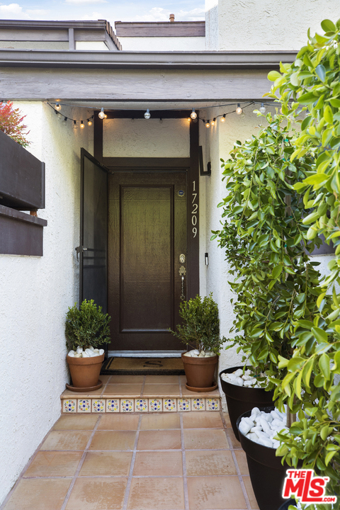 17209 Palisades Circle Pacific Palisades, California Cool and clean-lined, this beautifully remodeled contemporary townhome is a chic retreat within one of Pacific Palisades' most desirable Highland communities. Natural light bathes the living room, which boasts engineered hardwood flooring and a fireplace with a statement surround. Glass doors seamlessly open to a tiled patio extended outdoor living/dining room perfect for entertaining. The open layout also encompasses a gourmet kitchen/dining room featuring custom cabinetry, quartz countertops, and stainless steel appliances. Upstairs, the enviable primary suite has cathedral ceilings, an attached bath, and a private covered balcony. There is also a nursery off the bedroom, which easily converts to an office. Don't miss the other special details: A doggy spa is in the laundry room, and the garage doubles as a gym. And, the community offers access to resort-style amenities like a heated pool and spa, sauna, tennis courts, even a members-only private park with a large grassy field and playground (PDRA).