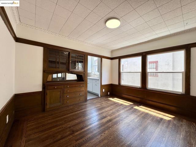 Unfurnished office featuring wainscoting, dark wood-type flooring, wooden walls, and ornamental molding