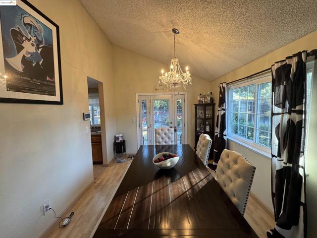 Dining area with wood finished floors, lofted ceiling, a textured ceiling, plenty of natural light, and a chandelier