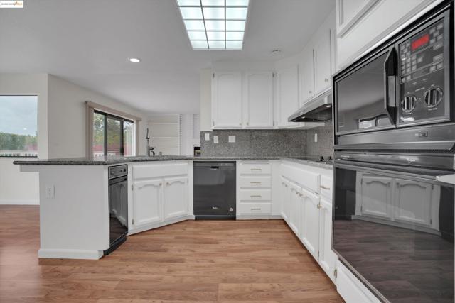 Kitchen featuring white cabinets, tasteful backsplash, black appliances, a peninsula, and recessed lighting