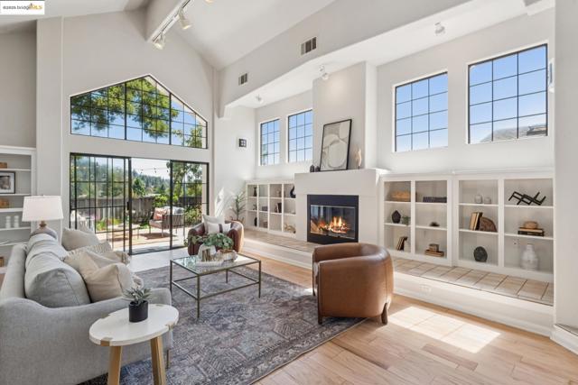 Living area with a glass covered fireplace, a high ceiling, plenty of natural light, light wood finished floors, and rail lighting