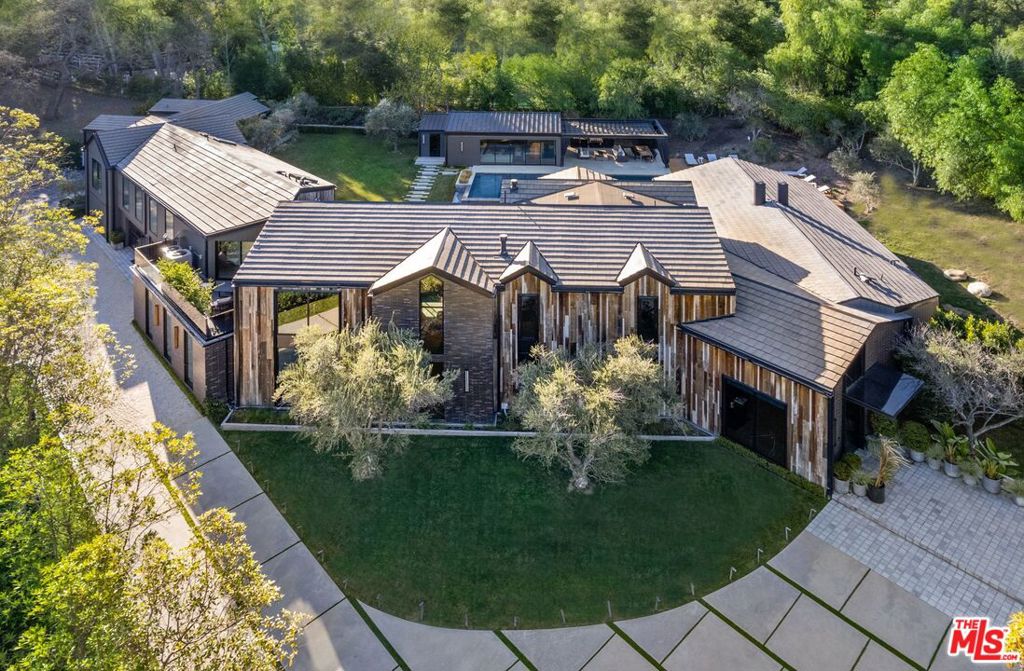 AUCTION BIDDING OPEN: Bidding ends 4/30. Previously Listed $17.495M. Current High Bid $12M. No Reserve. Showings Daily By Appt.  Welcome to this luxurious, modern farmhouse retreat in the ultra-coveted Hidden Hills community. Set on an acre and a half at the end of a private cul-de-sac in the guard-gated community, this estate offers the ultimate in privacy and security. The home's unique architecture, designed by Nobel LA, offers the best in indoor/outdoor living. The interior features double-vaulted wood ceilings, glass walls, and opulent details, such as the bespoke brass fireplace and dual Preciosa chandeliers. The stunning primary suite offers a fireplace with a sitting area, a designer walk-in closet, and a spa-like bathroom with dual chiseled stone vanities, a steam shower, and a soaking tub. The principal residence and a separate guest house are surrounded by an outdoor oasis offering a large flat lawn, a hardscape outdoor entertaining area, and a 65' swimming pool with a spa. Poolside cabana with indoor sitting area/game room, bathroom, built-in BBQ, fire pit, and video wall. Additional amenities include a home theater and fitness/music studio. Nestled within the tranquil Hidden Hills, this exquisite modern farmhouse retreat is not just a home; it's a testament to luxury living at its finest.