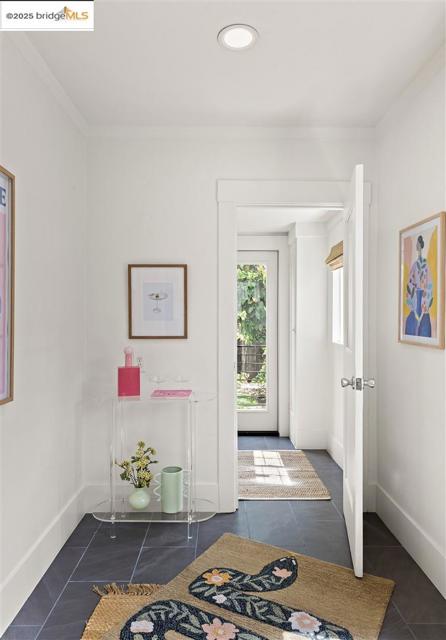 Foyer featuring dark tile patterned flooring and crown molding