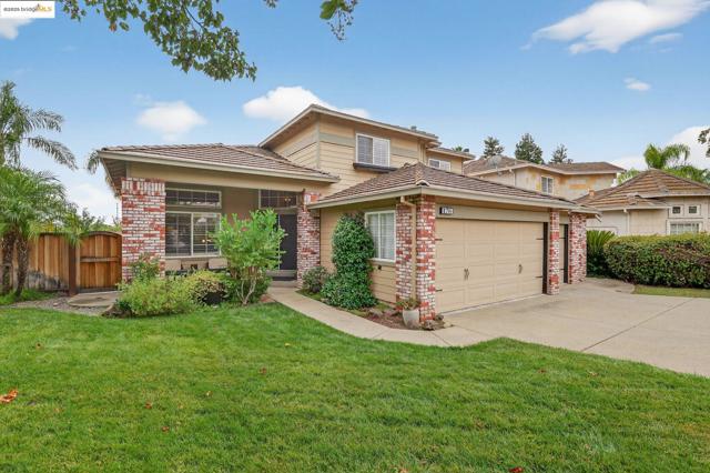 View of front of home with brick siding, driveway, an attached garage, and a gate
