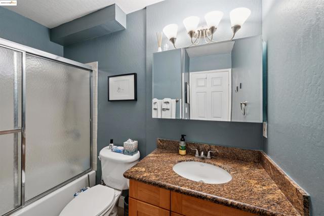 Bathroom featuring vanity, enclosed tub / shower combo, and a textured wall