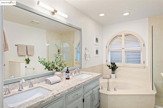 Full bathroom featuring a garden tub, double vanity, and a stall shower