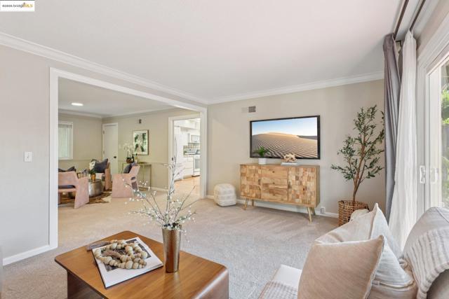 Living area with crown molding and carpet
