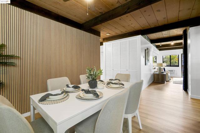 Dining area featuring wood walls, a wooden ceiling with exposed beams, and light wood-style floors