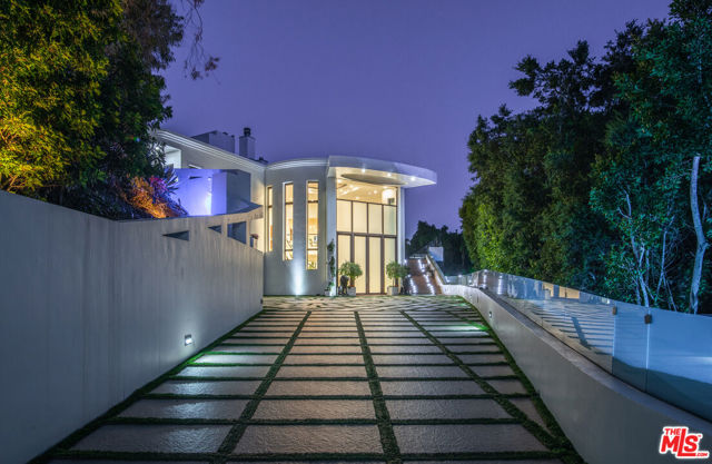 932 RIVAS CANYON Road Pacific Palisades, California Completely private compound located on an exclusive street behind a large gate is a resort-like oasis including an ocean view roof deck, hotel-style pool with a waterfall, large yard and putting green. A two story entrance leads to a dual, elegant staircase that takes you to an expansive living area with remote controlled sliding glass doors that extend the multiple living areas to a grassy private yard. An oversized chef's kitchen includes a walk in pantry. The dining area opens to the main level and can easily accommodate 16 guests or more. All guest rooms have an en-suite bath and fireplace. A large primary bedroom includes dual closets, large bathroom with dual sinks, a two-way fireplace, and glass doors to a patio and easy access to pool. Continuing upstairs, a private large rooftop is complete with a putting green, barbecue, and seating area. This exquisite home was built for California living and entertaining.