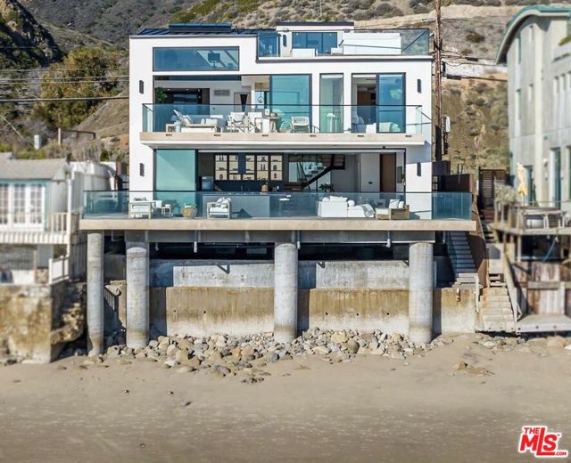 18954 Pacific Coast Highway Malibu, California This brand new 2022 construction home is a fully customized smart home, boasting panoramic ocean views, 57 ft of beach frontage and a custom-crafted contemporary design. The elegant beachfront property is close to Santa Monica and minutes to the Malibu Country Mart. The home was made with a steel frame to allow for a complete open floor plan with no obstructions of ocean views. The great room and kitchen hang over the Pacific Ocean, with automated Fleetwood doors that open on either side, to create an indoor/outdoor living space. The kitchen features all top of the line Miele appliances, soft close fridge, stone top burners and automatic shades throughout the home. All three ensuite bedrooms feature wide plank walnut flooring, custom closets with Italian leather shelves and natural limestone bathrooms. The grand primary suite features tall ceilings and a spa-like bath with soaking tub and opens to the outdoor oceanfront deck. On the rooftop deck, you'll find a modern imported hot tub, fire pit and all custom marine grade appliances for BBQing in style.