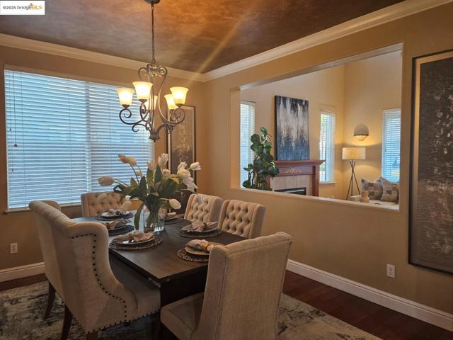 Dining area featuring ornamental molding, plenty of natural light, dark wood-type flooring, a tiled fireplace, and a chandelier