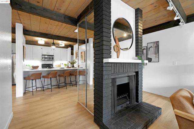 Living room featuring a fireplace, light wood finished floors, a wood ceiling with exposed beams, and rail lighting