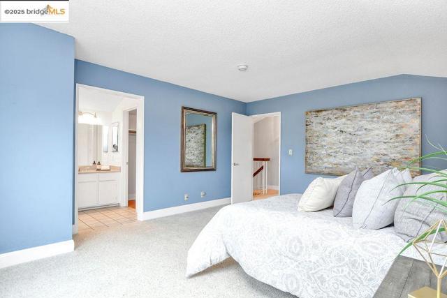 Bedroom featuring light colored carpet, a textured ceiling, and ensuite bath