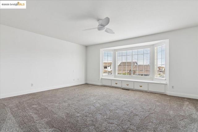Carpeted empty room featuring baseboards and a ceiling fan