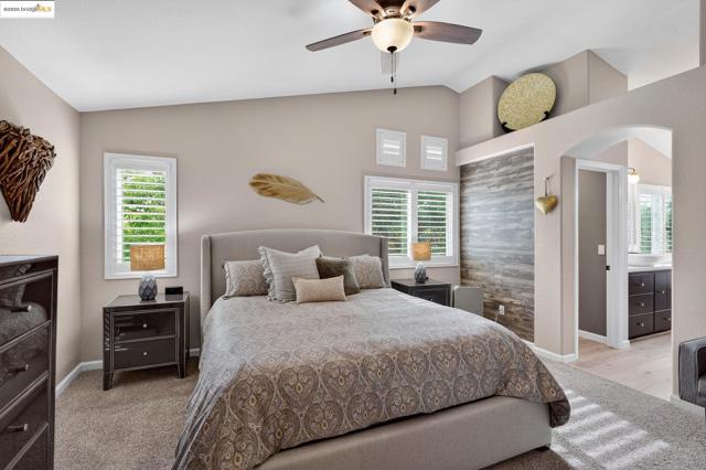 Bedroom featuring a ceiling fan, arched walkways, connected bathroom, and high vaulted ceiling