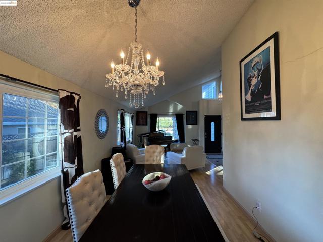 Dining area featuring wood finished floors, a textured ceiling, lofted ceiling, and a chandelier