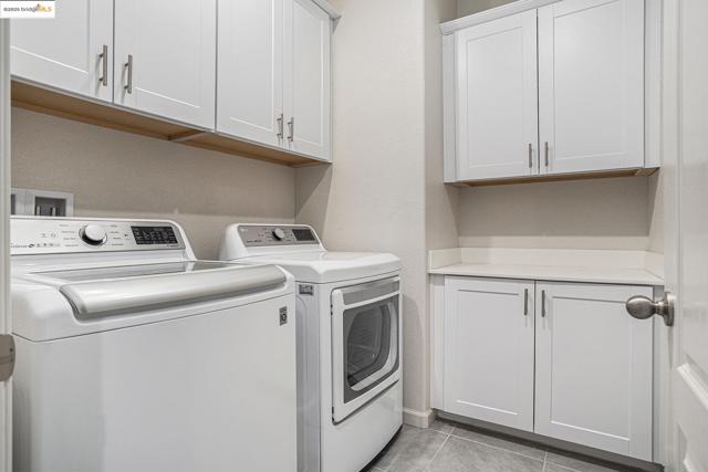 Laundry room featuring cabinet space, light tile patterned floors, and washing machine and clothes dryer