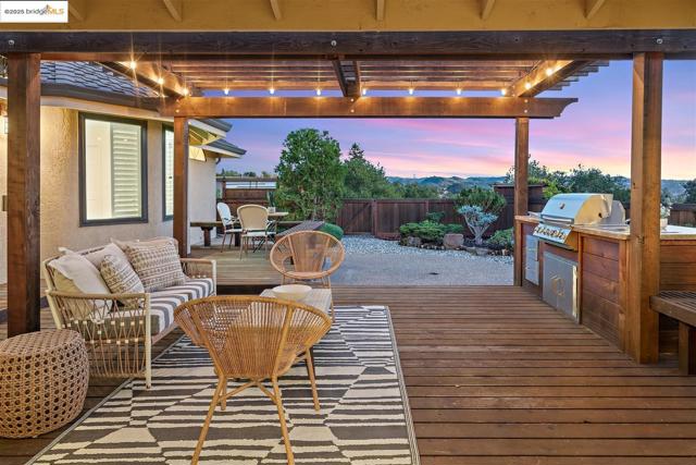 Deck at dusk featuring a fenced backyard, area for grilling, and an outdoor hangout area