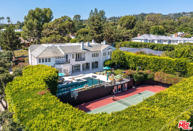 The finest quality and substance embody this grand three-level estate poised on an over 25,000 sq.ft. corner lot with a tennis court, on one of the best streets in the prime Beverly Hills Flats. Set behind gates with a semi-circular front driveway, this classic estate with apx. 10,000 sq.ft. of living space (BTV) is extremely private and offers an enchanting setting with manicured grounds, attractive brick-lined facade, and timeless authenticity, across 7 bedrooms, 8 baths and 3 powder rooms. Enter through the 12-foot double front doors into the impressive formal foyer with soaring two-story ceiling, dazzling chandelier, and intricate limestone  floors. The main level is complete with opulent public rooms, including a formal living room with fireplace, stately family room opening onto a private patio, huge formal dining room with fireplace and bar, beautiful rotunda breakfast room, and fabulous professional chef's kitchen with large center island, top-of-the-line Traulsen and Sub-Zero refrigeration, Wolf and Thermador stainless steel appliances, an industrial walk-in refrigerator, and butler's pantry. French doors from the breakfast room lead to a tremendous outdoor kitchen complete with abundant counter space and storage, dual Lynx barbeques, a refrigerator, and Ooni pizza oven. There are also two elegant, sunlit offices on the main level, one with a fireplace, as well as two formal powder rooms. Take the elevator or descend the rear staircase to the lower level that features a temperature-controlled wine cellar, laundry room, maid's suite, and incredible storage, along with a fully finished three-car garage. The upper-level includes five en-suite bedrooms plus a playroom/library and second laundry, and features the magnificent primary suite complete with vaulted ceiling, fireplace, three walk-in closets, and dual bathrooms, one with a sauna and the other with a soaking tub and separate steam shower.  Completely private with towering hedges and 150 mature trees, the backyard offers a serene setting and wonderful space for entertaining featuring sprawling covered and open patio space, lawn, rose garden, sparkling pool and spa, sunken championship lighted tennis court and adjoining tennis cabana/ADU with kitchenette and full bathroom.  Additionally, this exceptionally well-maintained home features a Vantage low voltage lighting system, movie projection system, voluminous storage across all three levels plus an extensive attic, and has had many recent upgrades, including: all 6 zones of Trane HVAC systems installed in last 1- 3 years; new ABS plumbing including the sewer line in 2023; new landscaping lighting throughout the property in 2023; many new appliances in last 3 years including washer-dryer, dishwasher, bar refrigerator; and new custom shades in 6 rooms.  Enjoy the world-class shopping, dining, and entertainment that Beverly Hills has to offer, all just moments away. Don't miss the opportunity to own this exceptional residence in one of the most coveted Los Angeles locations.