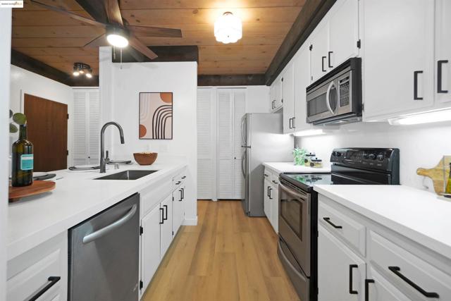 Kitchen featuring stainless steel appliances, wood ceiling, white cabinets, light wood-type flooring, and a ceiling fan