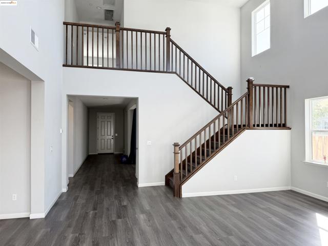 Entryway with a towering ceiling, healthy amount of natural light, dark wood-style flooring, and stairway