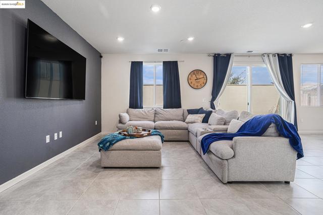 Living area with healthy amount of natural light, recessed lighting, light tile patterned floors, and a textured wall