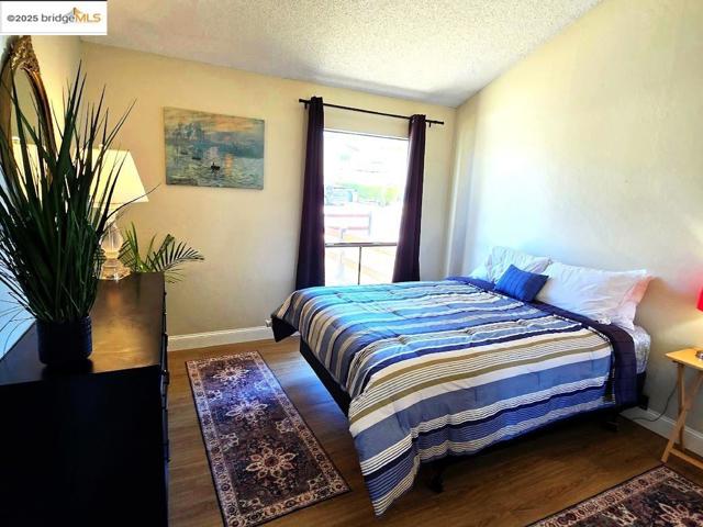 Bedroom with a textured ceiling and wood finished floors
