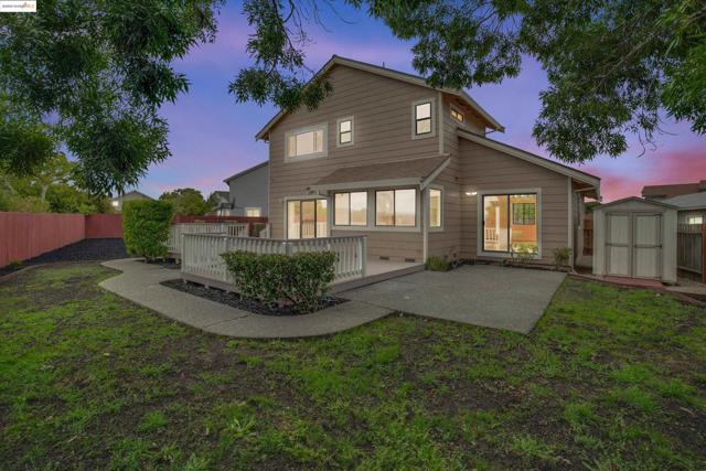 Back of house with a storage unit, a fenced backyard, a deck, and a patio area