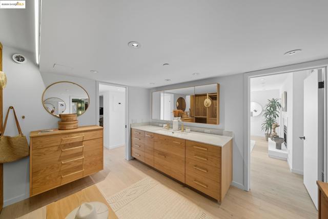 Kitchen with modern cabinets, light wood finished floors, brown cabinetry, recessed lighting, and light stone countertops
