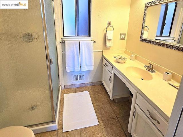 Bathroom featuring a stall shower, vanity, dark tile patterned floors, and a textured wall