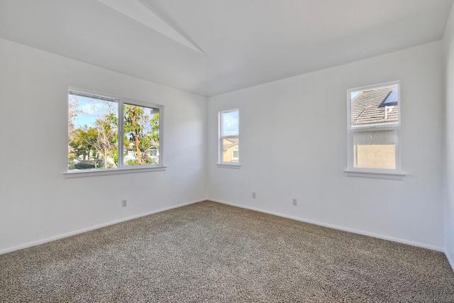 A vaulted ceiling plus several windows make for a bright and comfortable primary bedroom.