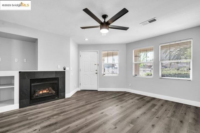Unfurnished living room featuring a tiled fireplace, wood finished floors, ceiling fan, and recessed lighting