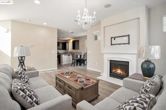Living room with recessed lighting, a glass covered fireplace, light wood finished floors, and a chandelier