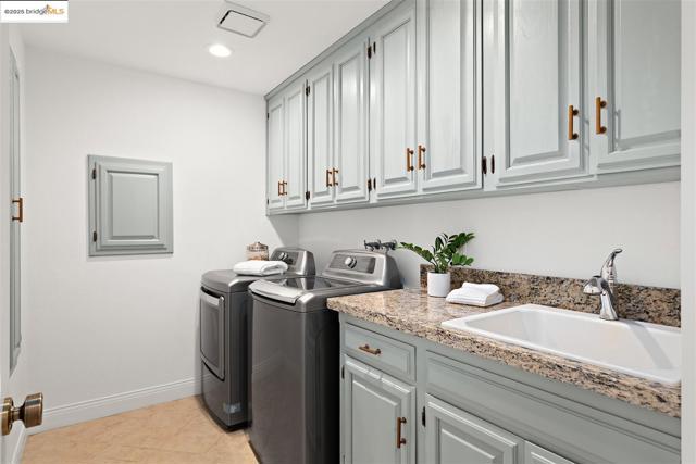 Washroom with light tile patterned flooring, washing machine and clothes dryer, cabinet space, and recessed lighting
