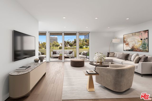 Modern living room with a white sectional, rounded accent chair, and floor-to-ceiling windows overlooking greenery and high-rises.
